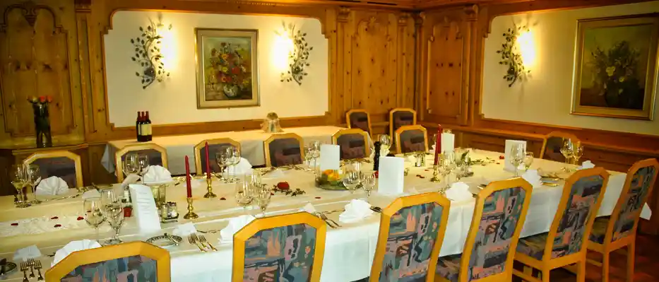 Schön dekorierter Tisch, im Taminastübli, im hintergrund 2 leuchtende Lampen an der Wand, in der mitte ein Bild mit Blumenstrauss.